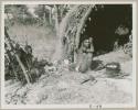 Woman beside her fire, cooking something in an iron pot