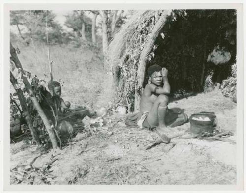 Woman beside her fire, cooking something in an iron pot