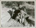 Woman sitting and holding a baby, another child beside her