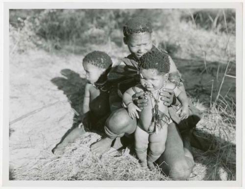 Woman sitting and holding a baby, another child beside her