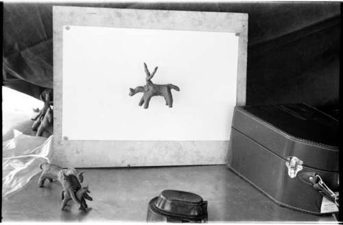 Plasticine model mounted on a board; several other Plasticine models to the left and a Bell and Howell movie camera case to the right