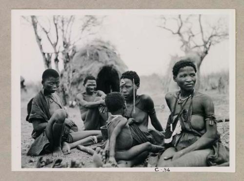 Group of people sitting, including !Ungka (sister of //Kushay), "/Qui Navel," //Kushay holding "Little ≠Gao," and //Khuga (daughter of "Gao Medicine," wife of Crooked /Qui)