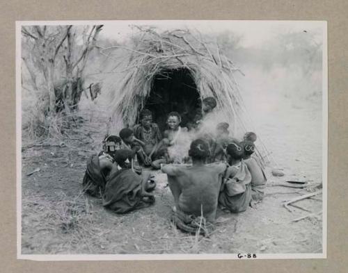 "Old Xama" sitting in front of a skerm beside her daughter, Zuma, and a group of people