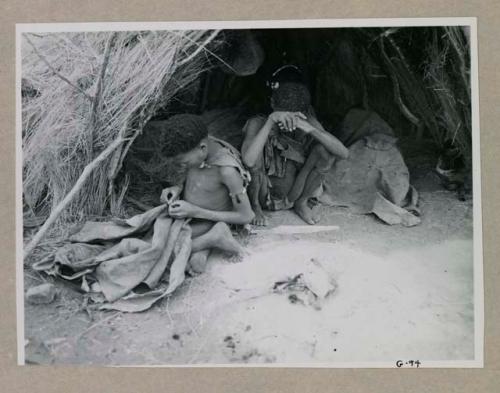 Boy sitting in front of skerm sewing, with another boy next to him

