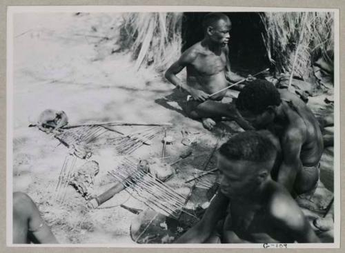 "Gao Helmet" and two other men working on arrows, applying poison from a little bone dish