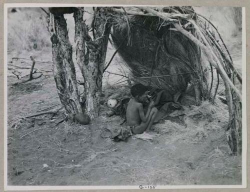 Boy sitting under a skerm built for shade
