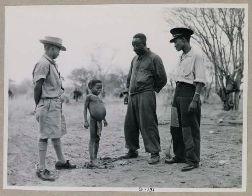 "Little /Gaishay" (son of ≠Toma and !U) standing with Ngani, a man who was the mechanic for the expedition, and Gao from Gam, an interpreter