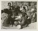 Group at Chukudu sitting; child drinking tsama melon juice
