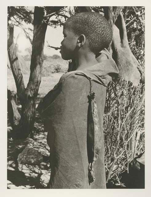 Child with long narrow bag hanging from kaross

