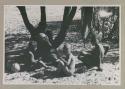 Adults and children sitting under tree
