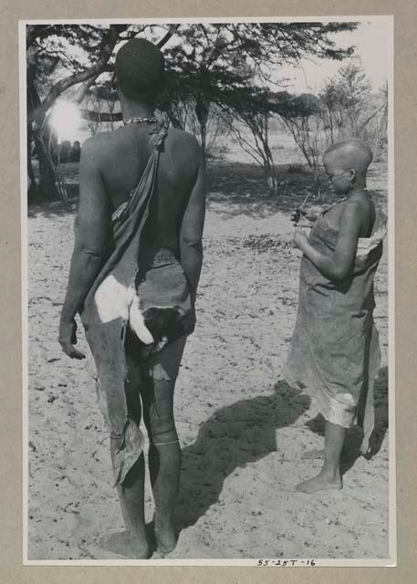 Person standing, seen from behind and woman standing to the side
