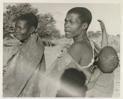 Mogatsiposi with a child on her back, standing with another woman, close-up
