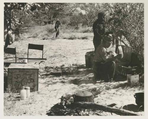 Camp scene, three expedition members in background
