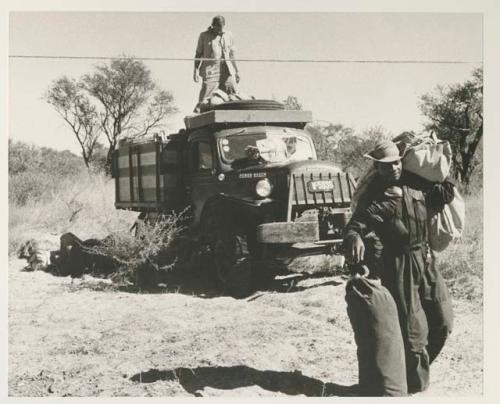 Bill Donnellan on truck throwing things down; Kernel Ledimo and Philip Hameva carrying items
