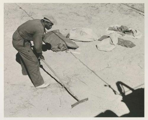 Kernel Ledimo raking the place where Lorna Marshall's tent was to be set
