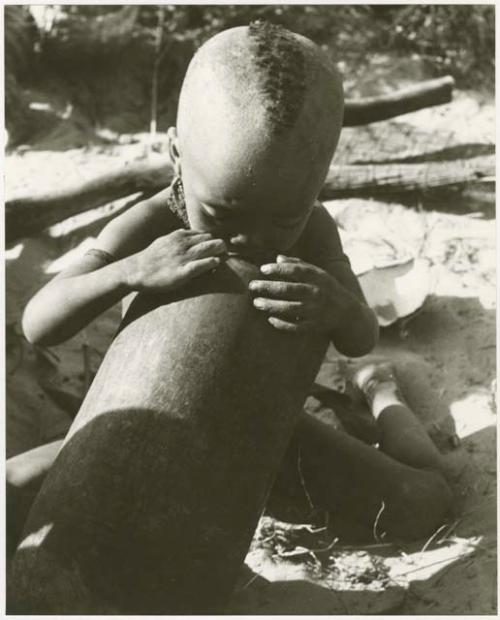 N!whakwe licking mortar (mortar is also a cement like compound) (print is a cropped image)