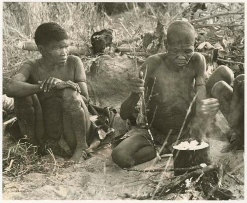 DaSi!Na and /Twikwe cooking something in a pot, two boys sitting (print is a cropped image)