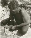 Oukwane scraping sansevieria fibers to make a cord (print is a cropped image)