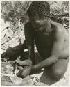 Oukwane scraping sansevieria fibers to make a cord (print is a cropped image)