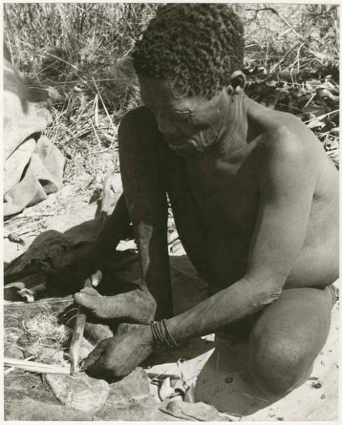 Oukwane scraping sansevieria fibers to make a cord (print is a cropped image)