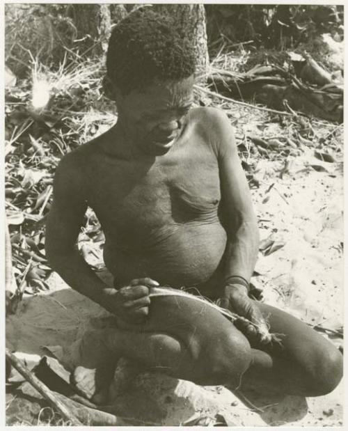 Oukwane rolling sansevieria fibers on his leg making cord (print is a cropped image)