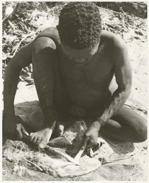 Oukwane scraping sansevieria fibers to make a cord (print is a cropped image)