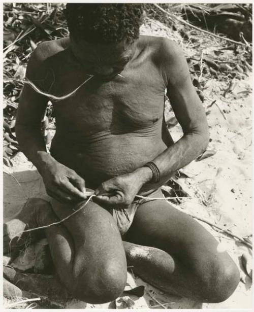 Oukwane rolling cord on his leg, showing the beginning of a splice (print is a cropped image)