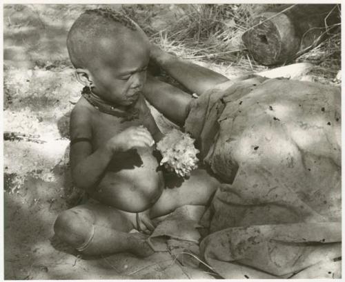 N!whakwe sitting with a cucumber (print is a cropped image)