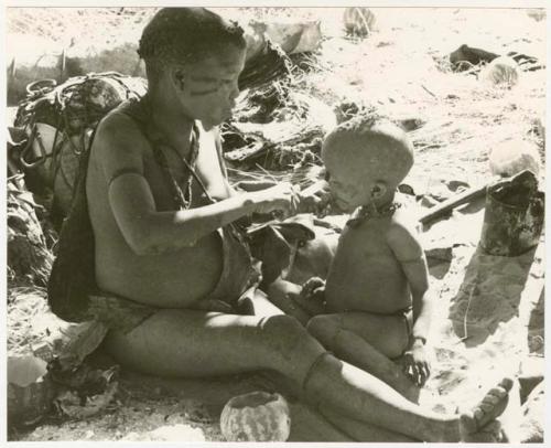 Tsekue giving N!whakwe a piece of meat, cutting it off at his lips with a knife (print is a cropped image)