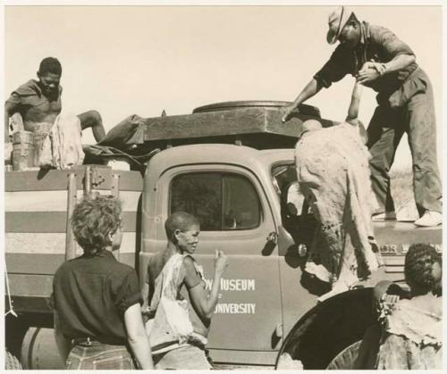 Oukwane on expedition truck, Kernel Ledimo helping someone up; Elizabeth Marshall Thomas and other people in front of expedition truck (print is a cropped image)