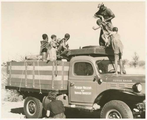 Group of people standing in the back of an expedition truck, with Kernel Ledimo helping them (print is a cropped image)