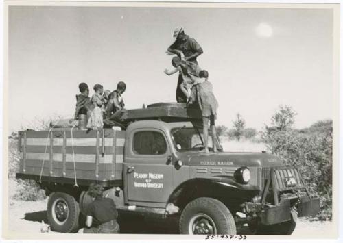 Group of people standing in the back of an expedition truck, with Kernel Ledimo helping them