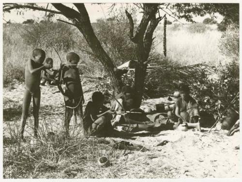 /Gaiamakwe and //Kwaiǂkabe shooting at target, !Ou/ke standing with bow in hand, /Twikwe and DaSi!Na sitting at their fire (print is a cropped image)