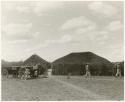 Two men walking away from a cart (print is a cropped image)