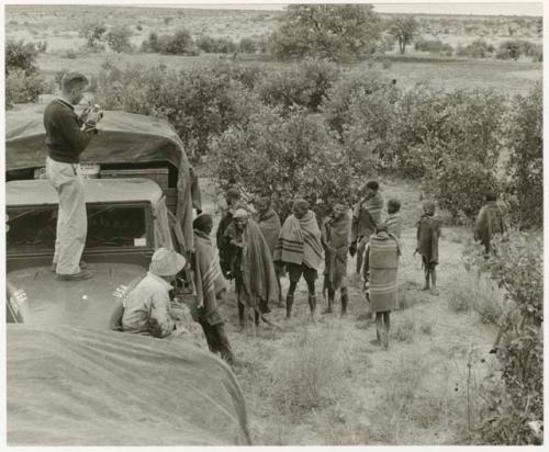 Group standing by expedition truck, two expedition members on top of truck (print is a cropped image)