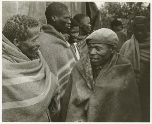 Gishay talking to one of the men from Lutlhe, people standing in the background (print is a cropped image)