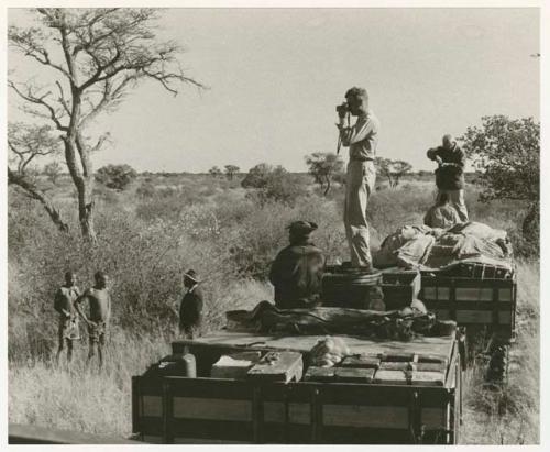 Wilhelm Camm talking to two men; Daniel Blitz photographing from top of the truck with Laurence Marshall and two expedition members (print is a cropped image)