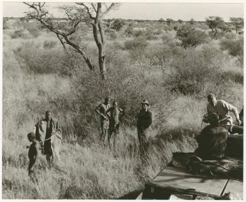 Man being led by a man with a stick, Wilhelm Camm standing with two other men (print is a cropped image)