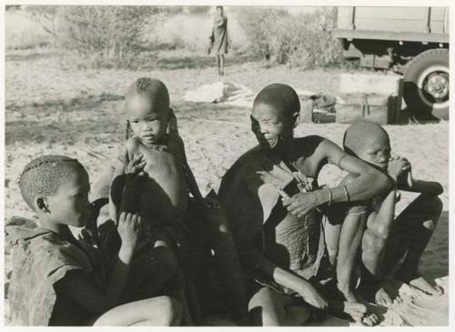 /Gaiamakwe, N!whakwe in front of Tsekue, /Twikwe, and !Oukabe, expedition truck in background (print is a cropped image)