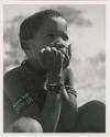 "Individuals I [Lorna Marshall] can't identify": Boy sitting, with his hands on his cheeks (print is a cropped image)