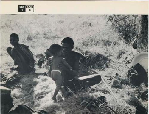 [No folder title]: "Gao Medicine" sitting and holding Debe, his son /Gaishay watching (print is a cropped image)