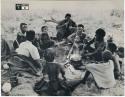 [No folder title]: //Kushay, "Little ≠Gao", !Ungka, and other unidentified people seated around a pot on a fire while "Old Gau" stirs the pot (print is a cropped image)