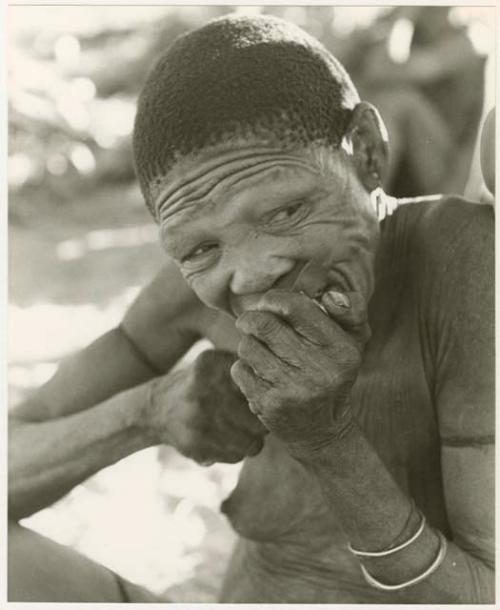 /Twikwe cutting meat off at her lips, close-up (print is a cropped image)