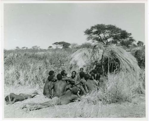 [No folder title]: Group of people sitting and telling stories, including "Lame ≠Gao," ≠Gao (Khwo//o-/Gasa's husband), "Gao Medicine," an unidentified person, ≠Toma, !Naishi, "Old Xama," "Gao Helmet," "Old Demi" lying down, Crooked /Qui, Gao (Debe's son, Zuma's husband), and ≠Toma (!Naishi's son) (print is a cropped image)