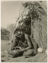 "Band 5, Khuan//a the Musician (85)": Khuan//a sitting in front of a skerm and playing the //guashi (print is a cropped image)