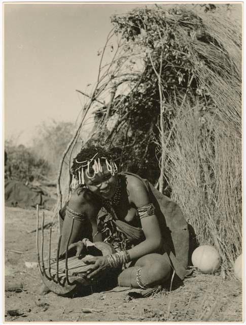 "Band 5, Khuan//a the Musician (85)": Khuan//a sitting in front of a skerm and playing the //guashi (print is a cropped image)