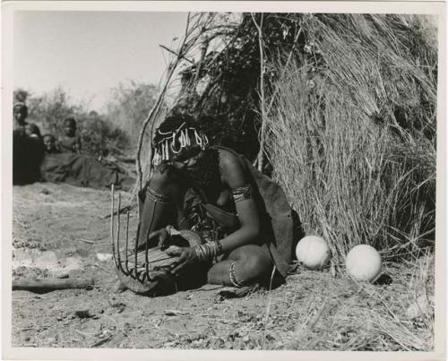 "Band 5, Khuan//a the Musician (85)": Khuan//a sitting in front of a skerm and playing the //guashi (print is a cropped image)