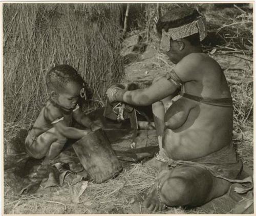 "//Kushay II #32, 2nd wife of Gao #28": //Kushay ("Gao Helmet's" second wife) and Xama (her little daughter) playing with the mortar, sitting beside their skerm (print is a cropped image)