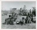 "Boys groups  /Gunda & //Ao": N!ai playing a //guashi, with a large group sitting in "Gao Medicine's" werft  (print is a cropped image)