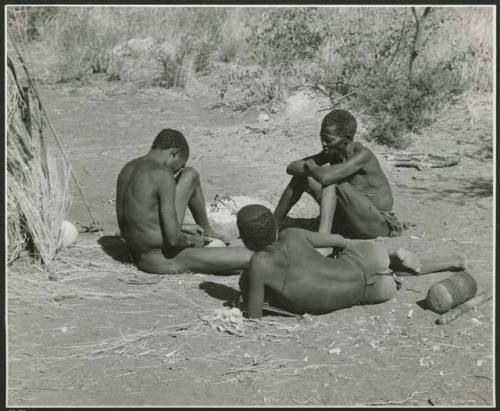 Groups [of] men: "/Qui Navel" making arrows by a fire and an unidentified person and "Old Gau" sitting to the right, watching him (print is a cropped image)